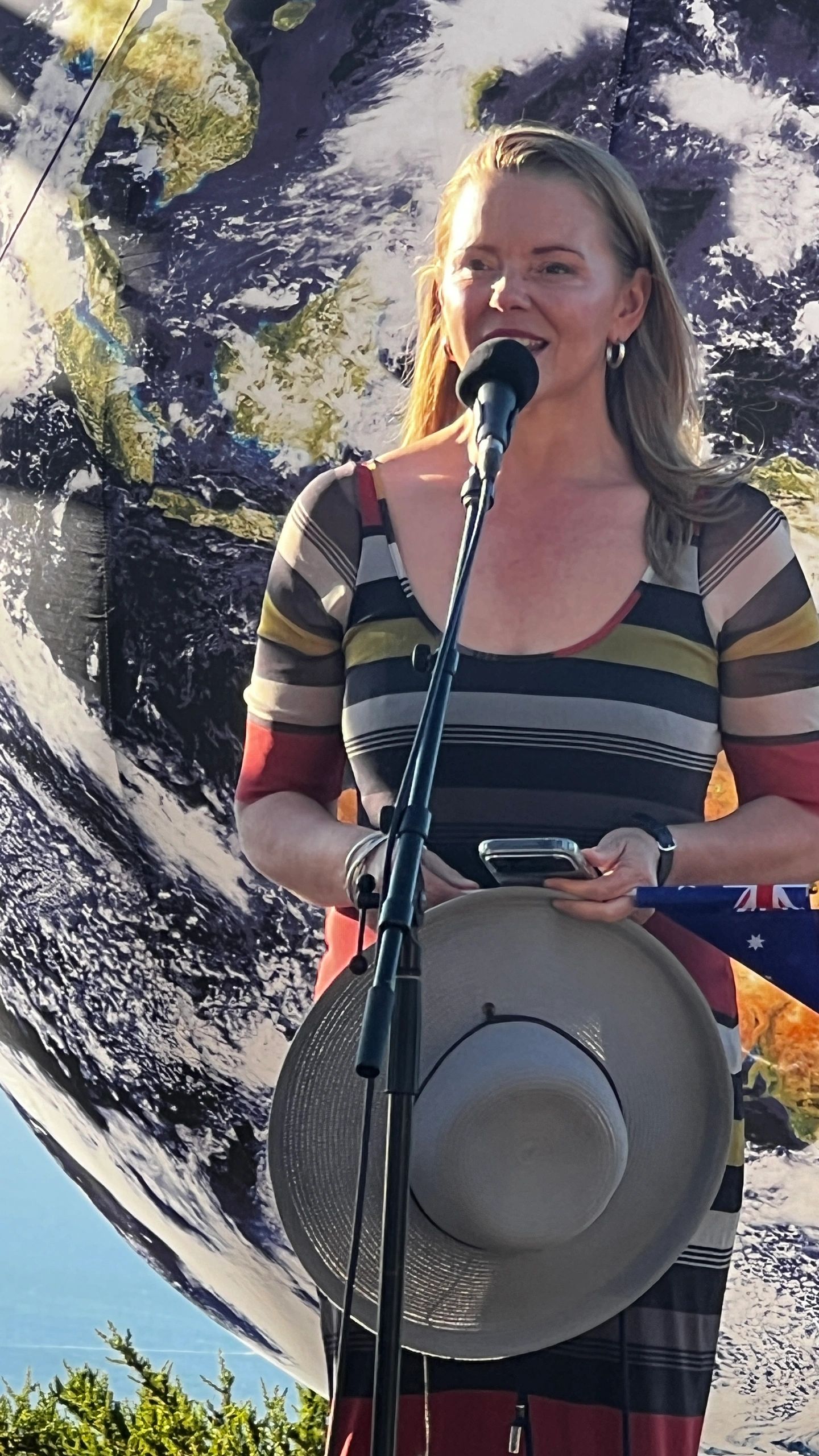 Speaker at an outdoor ceremony with the Earth globe behind